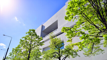 Modern white concrete building walls against blue sky. Eco architecture. Green trees and concrete...
