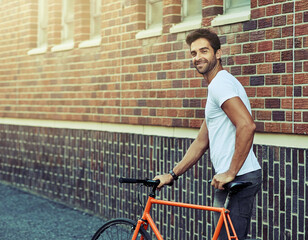 Smile, bicycle and portrait of man by brick wall in city for sightseeing on vacation or adventure....