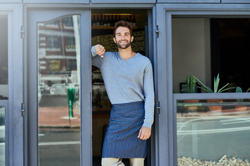 Happy, small business and portrait of man at coffee shop for service industry, welcome or smiling. Confidence, entrepreneur and male barista with apron at cafe entrance, doorway or front door