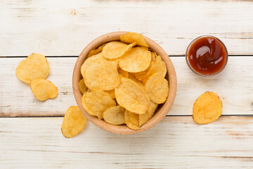 Appetizing potato chips on wooden background, top view