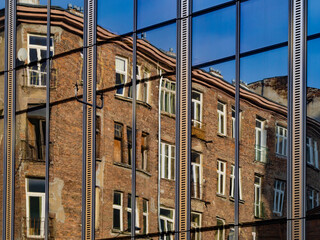 Obraz premium An old brick tenement house and a modern building made of steel and glass.