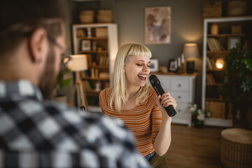 Adult woman sing karaoke on microphone and man hold bottle of beer