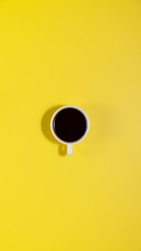 Stop motion animation of coffee cup filling and coffee beans disappearing on yellow background