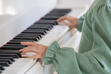 A young girl in green dress is playing the piano