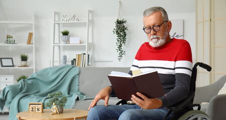 Senior man in wheelchair reading book at home