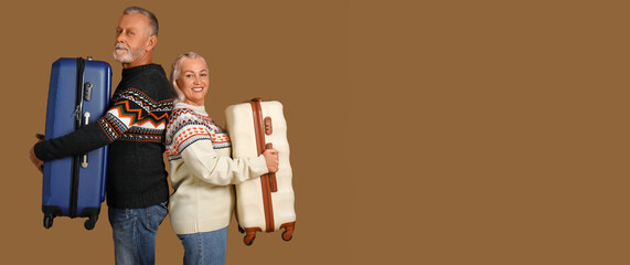 Senior couple with suitcases on brown background
