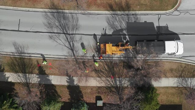 Aerial view of Tree cutting services worker loading cut tree branches into the wood chipper machine for shredding