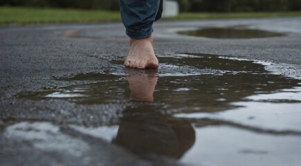 A person standing in a puddle, water reaching their feet, creating a serene and reflective scene.

