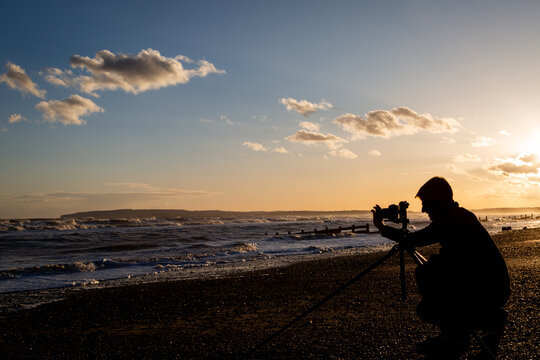 Silhouette of a professional photographer using a tripod to capture long exposure landscape images on Camber sands beach