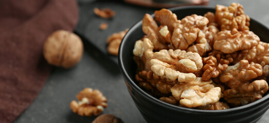 Bowl of tasty walnuts on grey background