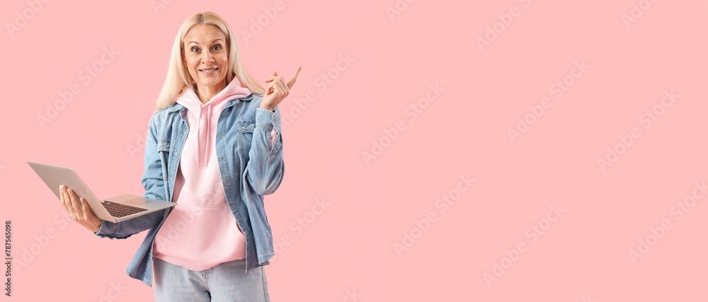 Poster mature female programmer with laptop showing something on pink background with space for text