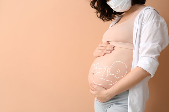 Young pregnant woman in medical mask on color background