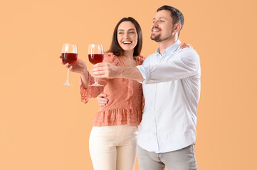 Happy young couple with glasses of wine on beige background