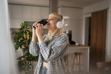 Young woman with headphones listen music and sign on mobile phone happy