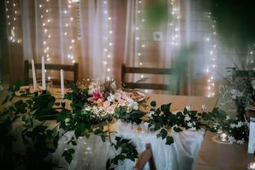 Valmiera, Latvia- July 28, 2024 - Elegant table setting with a floral centerpiece, candles, and fairy lights, creating a festive and cozy atmosphere.