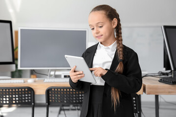 Little girl studying with tablet at school computer lab