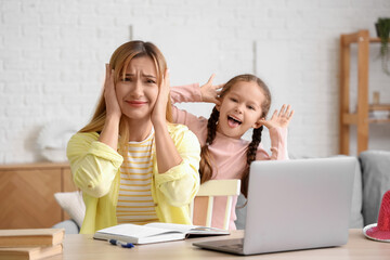 Working young woman stressed of her naughty little daughter at home