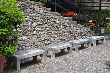Row of Modern Stone Benches with Rough Stone Wall in Outdoor Castle Courtyard