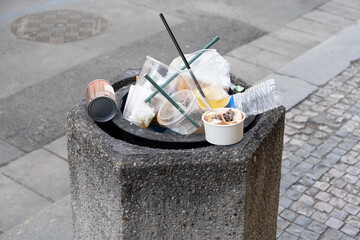 Concrete Litter Bin Overloaded. Plastic and paper waste an overflowing trash bin on a tourist...