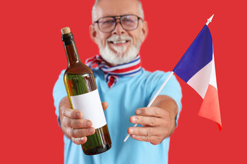 Senior man with flag of France and champagne on red background, closeup