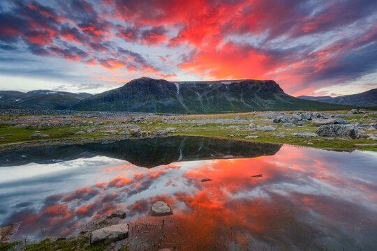 Mountain range reflected in the lake in evening mood with red clouds, Gaellivare, Norrbottens laen, Sweden, Europe
