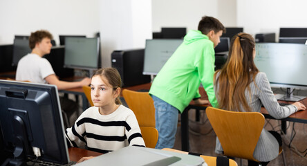 Portrait of female schoolgirl at computers in university computer class