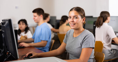 Positive young woman studying computer science in computer class. Woman learning to code.