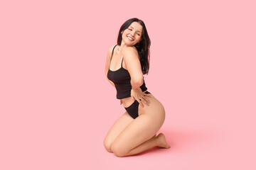 Fototapeta na wymiar Body positive young woman in underwear sitting on pink background