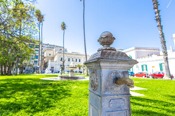 Old water tap on the virgilio park in brindisi, surrounded by buildings and cars. Park in the...
