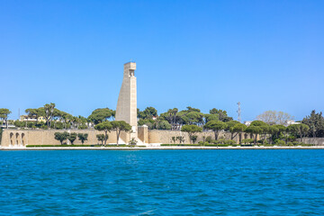 Tall monument of Brindisi port looking from lungomare walkway on a warm sunny spring day. Blue...