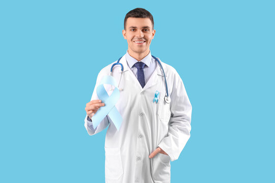 Male doctor with blue ribbon on color background. Prostate cancer awareness concept