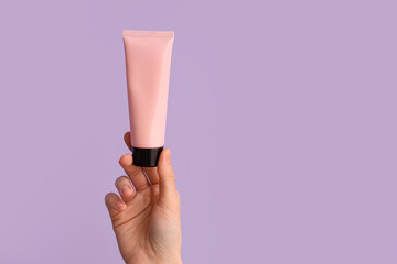 Female hand with tube of natural cream on lilac background, closeup