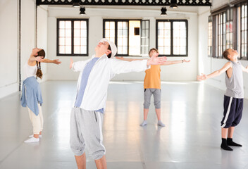Group of teenagers training at dance class, practicing contemporary dance moves