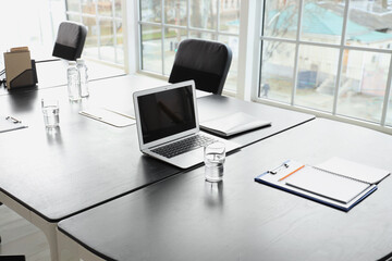 Laptop with glass of water on table prepared for meeting in office