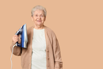 Happy senior woman with iron on brown background