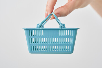 小さな買物かごを持つ女性の手元