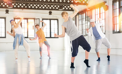 Teenage girl and boys having dance training in studio, performing hip hop elements