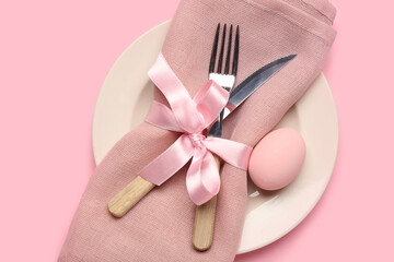 Stylish table setting with Easter egg, napkin and cutlery on pink background