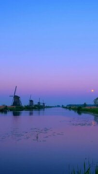 Windmills at famous tourist site Kinderdijk in Holland after sunset with dramatic sky. Kinderdijk , Netherlands. Camera pan