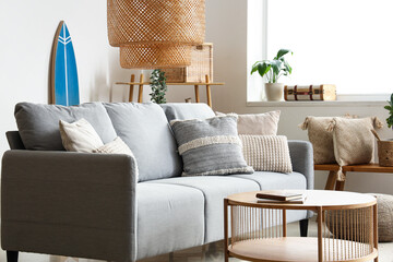 Obraz premium Beautiful interior of light living room with comfortable sofa, table, carpet and lamp