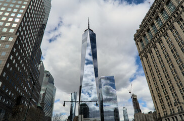 downtown manhattan skyline view (wide angle photo with one world trade center skyscraper in the middle) financial district new york city famous landmark travel destination glass reflecting blue sky