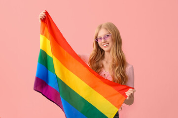 Beautiful young happy woman with LGBT flag on pink background