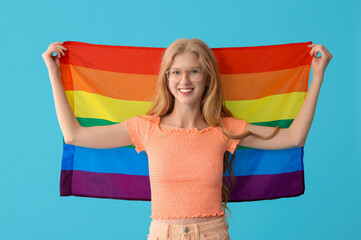 Beautiful young happy woman with LGBT flag on blue background