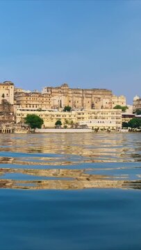 Udaipur City Palace on the bank of beautiful lake Pichola - Rajput architecture of Mewar dynasty rulers of Rajasthan. Water ripples reflect Palace view. Udaipur, India