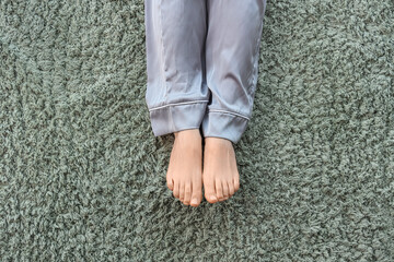 Barefoot woman on green carpet at home, top view