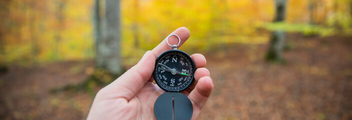 Compass in man's hand, in the autumn forest - obrazy, fototapety, plakaty