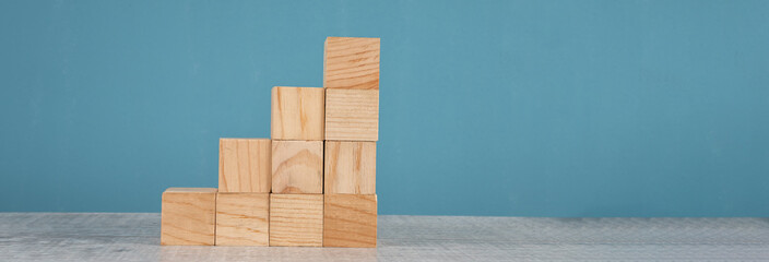 wooden block stacking as step stair on blue background. Business concept for growth success process.