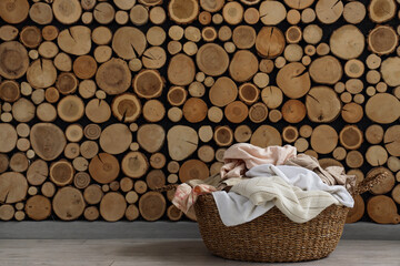 Wicker laundry basket with clothes near wooden wall