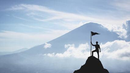 Silhouette of a man on the peak of a mountain, concept of victory and achievement