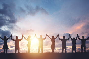 Silhouette of people holding hands against sunset background, concept of peace and victory - obrazy, fototapety, plakaty